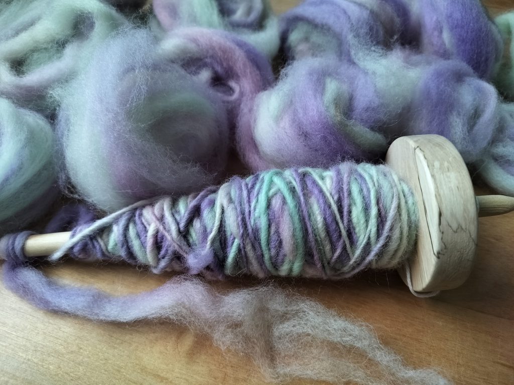 Värttinä ja käsin kehrättyä, pastelliväristä lankaa