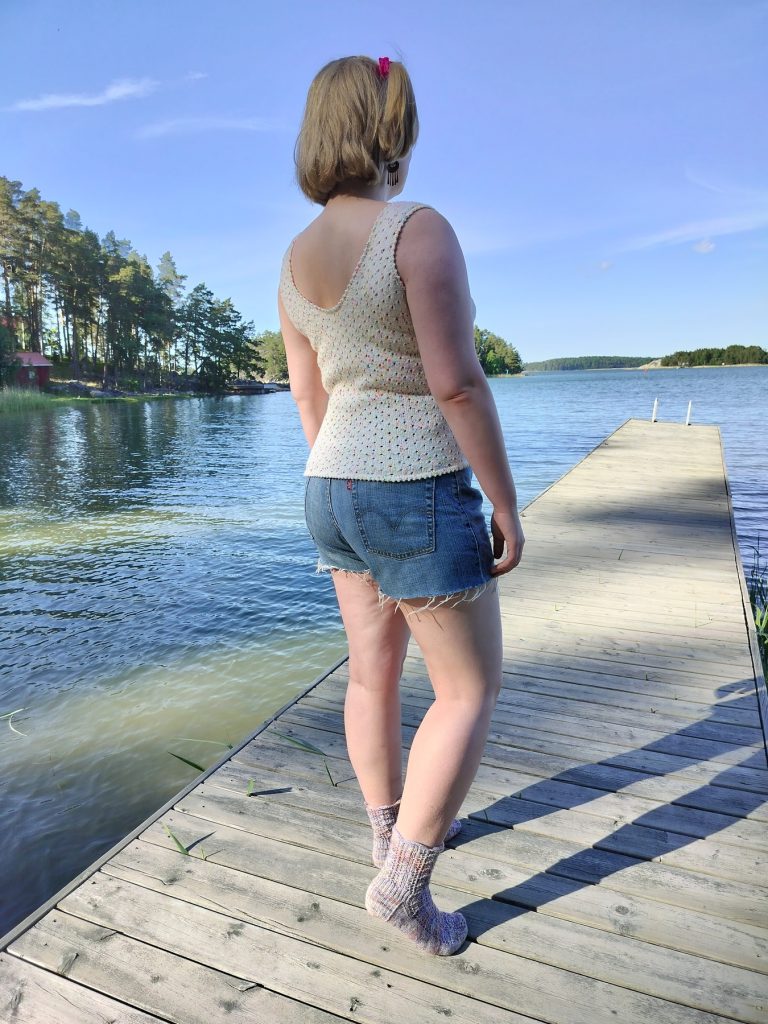 Kirjava pitsitoppi, neuletoppi. Kuva on otettu laiturilla aurinkoisena päivänä.